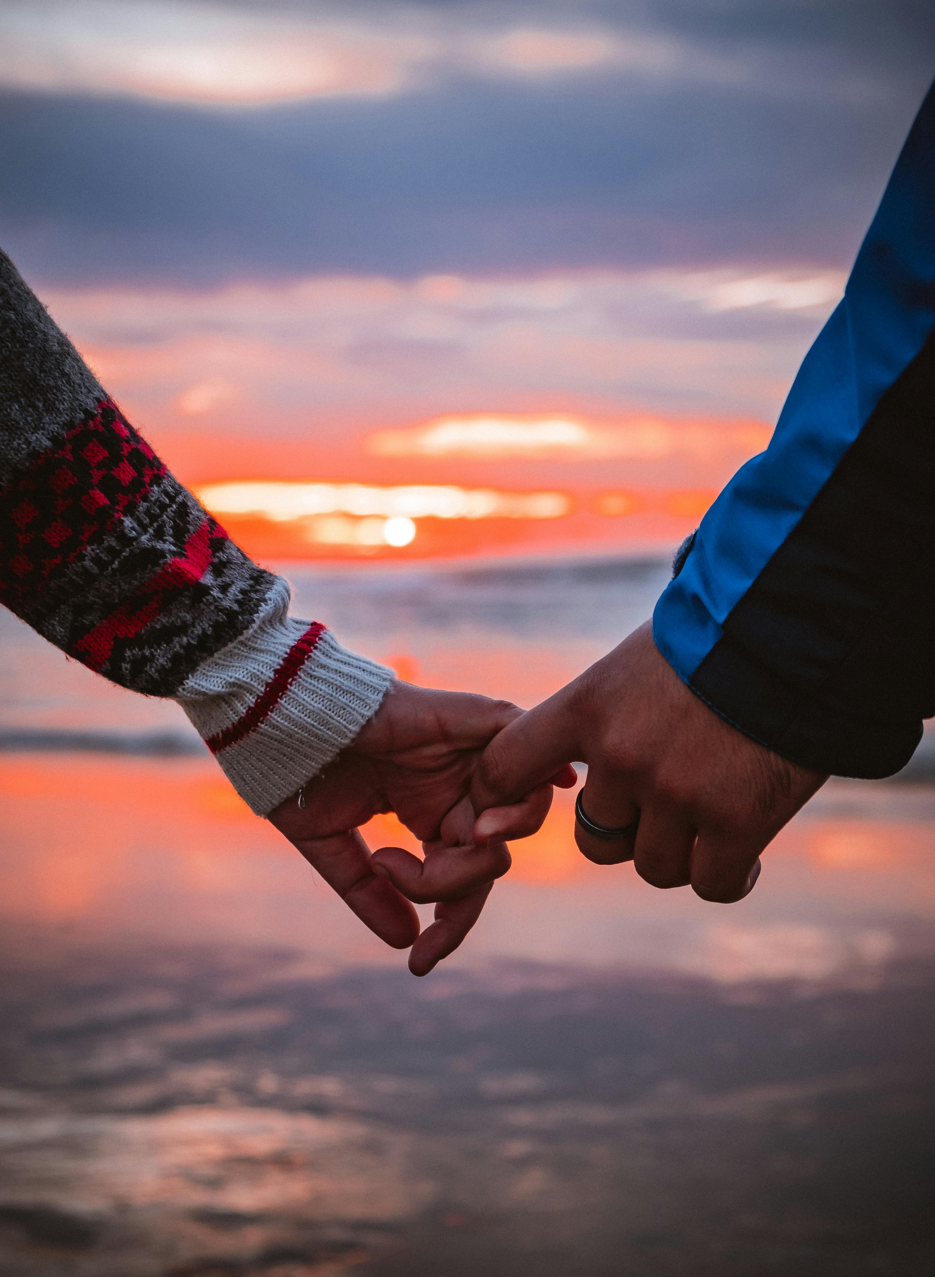 Hands reaching for each other at sunset